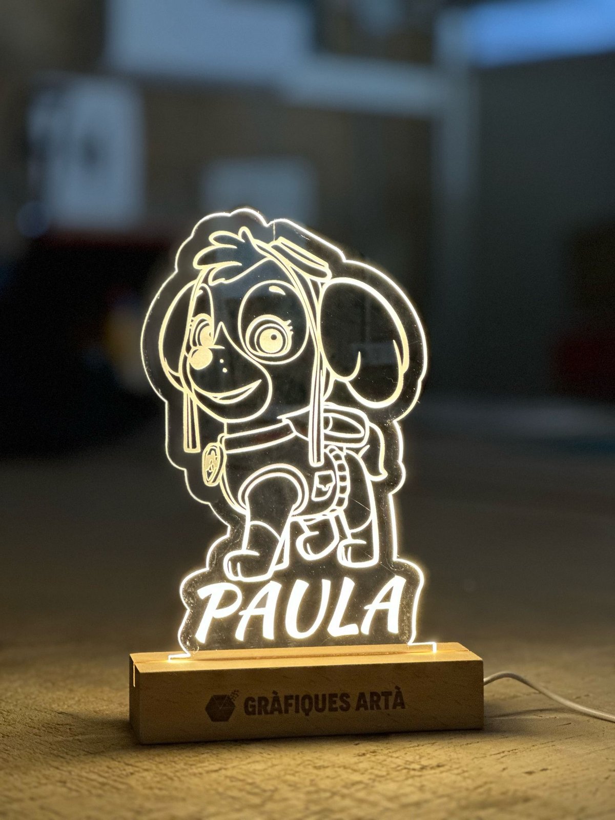 Làmpara gravada al làser — Paula Làmpara LED de metacrilat gravada amb un personatge i el nom Paula, amb base de fusta de Gràfiques Artà
